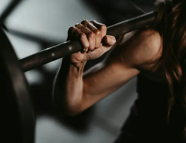 Ab Dezember 2026: glockna – das wohl coolste Hotel in Fusch Frau hält Langhantelstange beim Krafttraining im Fitnessstudio