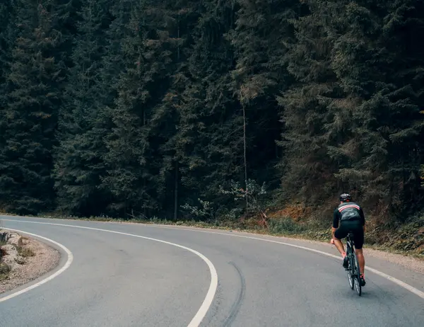 Ab Dezember 2026: glockna – das wohl coolste Hotel in Fusch Radfahrer auf kurviger Straße neben dichtem Wald