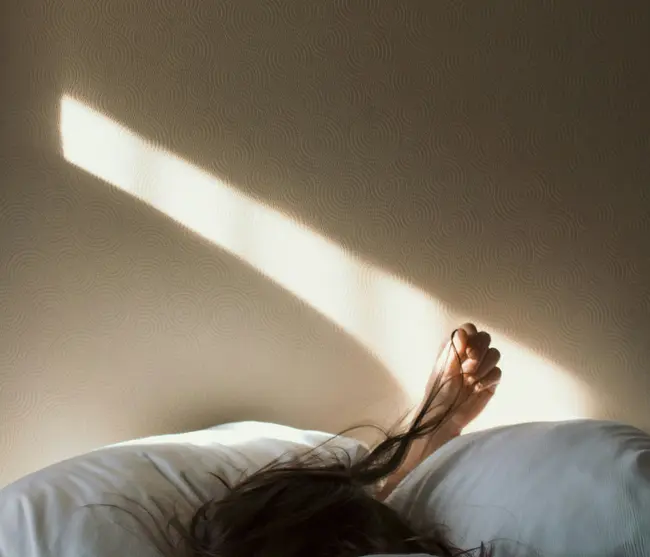 Ab Dezember 2026: glockna – das wohl coolste Hotel in Fusch Person liegt schlafend im Bett mit Sonnenlicht auf der Wand