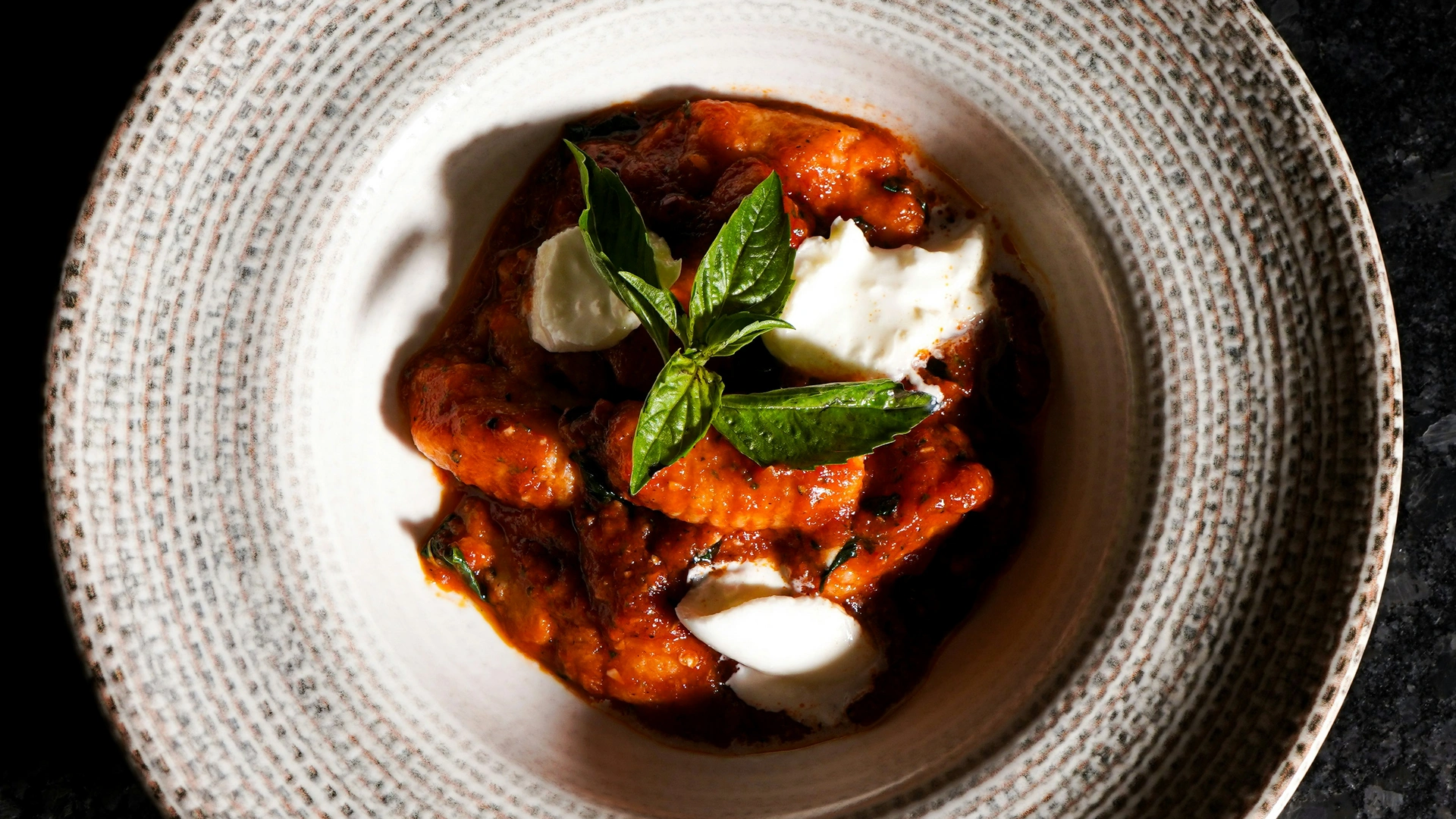 Ab Dezember 2026: glockna – das wohl coolste Hotel in Fusch Gnocchi mit Tomatensauce, Mozzarella und Basilikum in einem gemusterten Teller