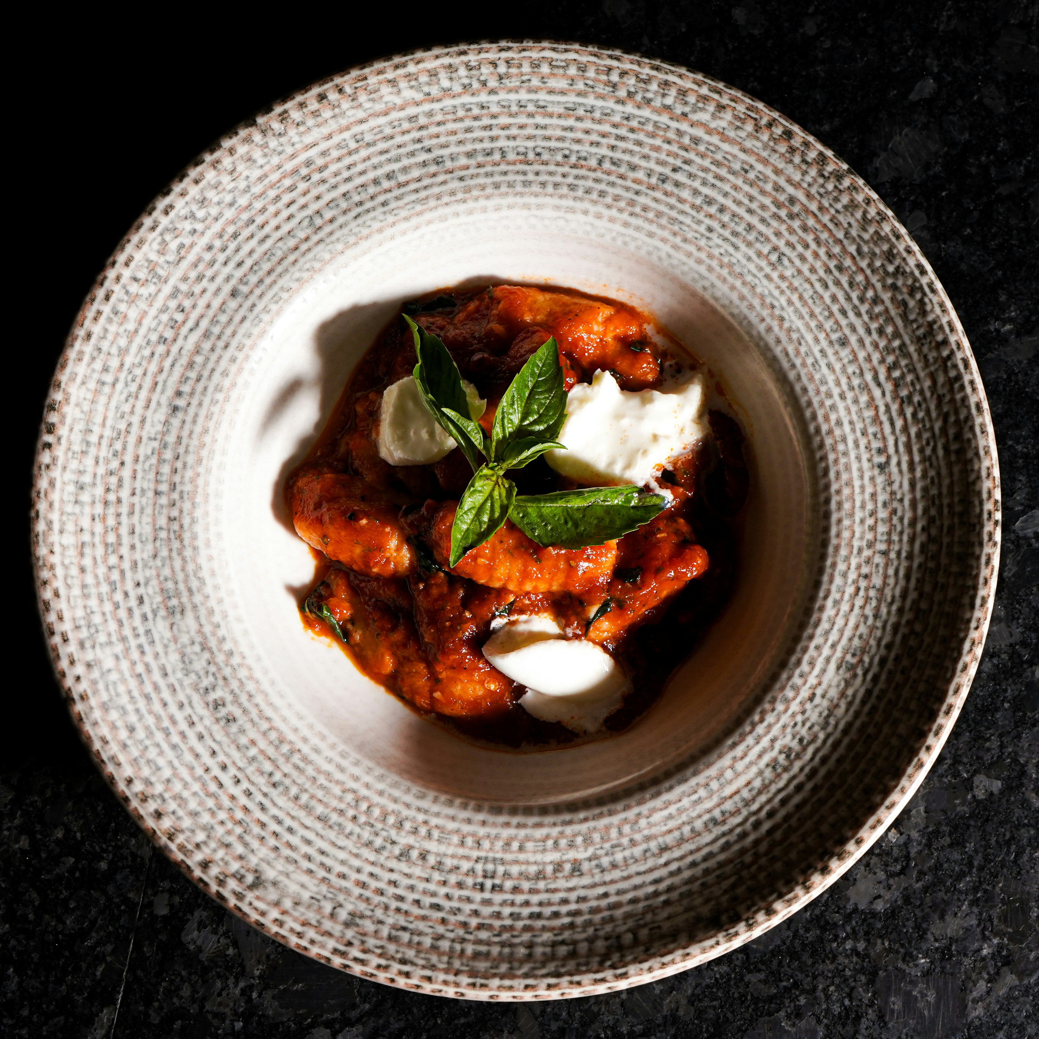Ab Dezember 2026: glockna – das wohl coolste Hotel in Fusch Gnocchi mit Tomatensauce, Mozzarella und Basilikum in einem gemusterten Teller